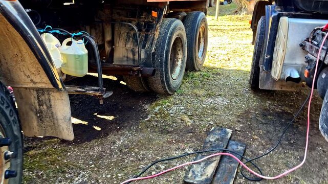 Emergency roadside assistance with two trucks jump starting and transferring diesel fuel