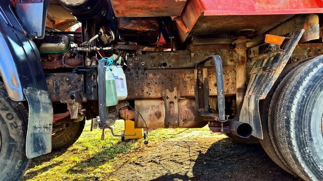 Detailed view of a heavy vehicle's undercarriage showing rust, wheels, and engine parts