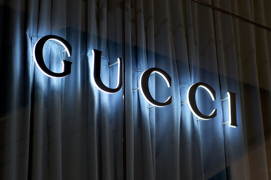 Illuminated Gucci sign with blue curtain background
