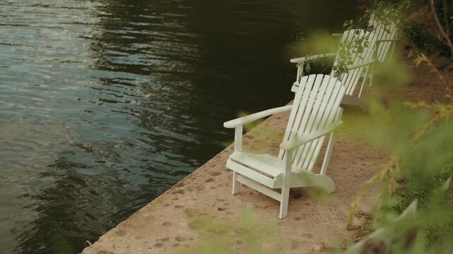 White Adirondack chairs sit along Douro River bank inviting quiet riverside relaxation