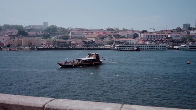 Rabelo boat carrying tourists sailing on Douro River with Porto and Vila Nova de Gaia cityscape in background Portugal