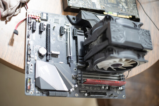 Close look at a computer motherboard with a cooling fan and components, taken in a workspace during daytime