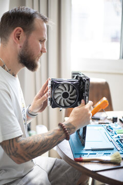 Man works on computer hardware assembly in a well-lit room during daytime in a home setting