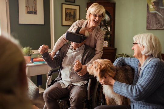 Senior friends using vr headset together at home
