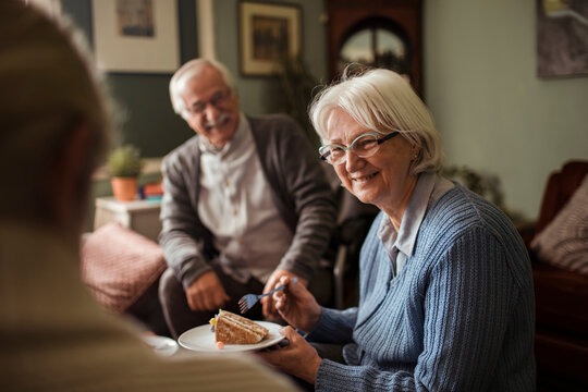 Smiling senior friends enjoying cake at home