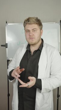 Scientist in white coat explaining chemical formulas on board