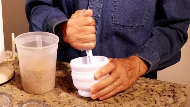 Man using with a white plastic mortar and pestle crushing flax seeds