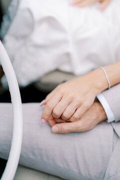 Intimate scene showing two hands clasped softly with wedding rings present