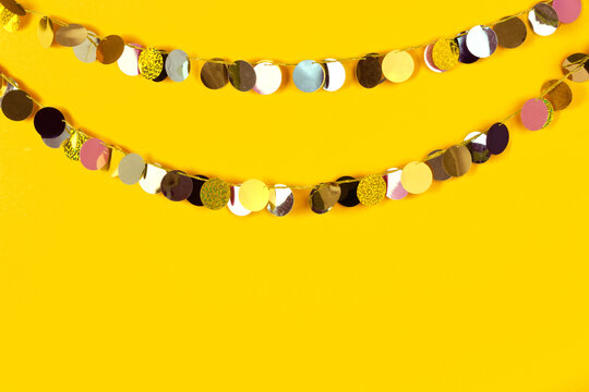 Metallic sequin disc garland strands on yellow background.