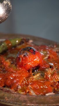 Traditional Turkish Iskender kebab with tomato sauce and melted butter being poured.