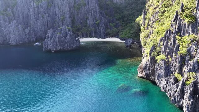 A scenic, secluded beach is surrounded by rugged, karst limestone in El Nido. This area in the Philippines is a popular vacation destination due to its coral reefs, beaches, and hidden lagoons.