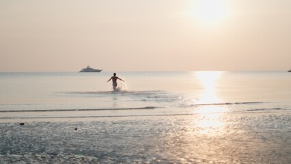 Fototapeta premium Man running in ocean at golden hour, celebrating freedom and luxury travel lifestyle