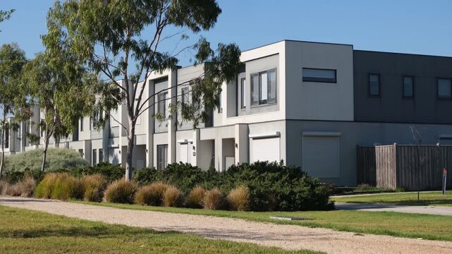 Modern townhouses with contemporary architecture in a suburban development; featuring native Australian landscaping, eucalyptus trees, and a gravel walking path in the foreground. Melbourne Australia