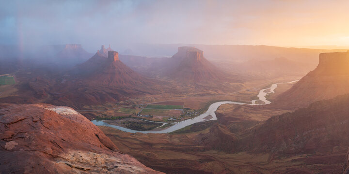 Aerial view of the winding Colorado River flowing through the red rock mesas and buttes of Castle Valley under a misty golden sky Castle Valley, Utah, United States.