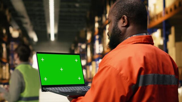 Chroma key screen with black worker operating packages and cargo in warehouse facility, operational workflow and shipping activity assures order fulfillment operations for manual labor.