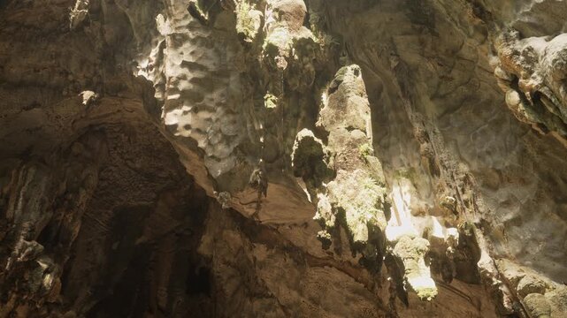 Dramatic interior of Batu Caves showcasing massive rock formations shaped by erosion and constant water flow.