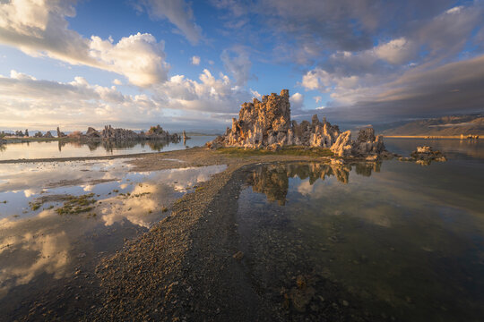Aerial view of the unique tufa towers at Mono Lake with dramatic cloud reflections on the calm water surface and mountains in the distance Mono County, California, United States.