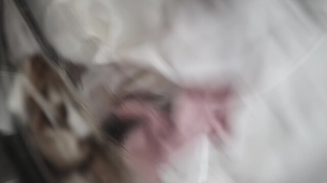 Soft fabrics in a washing machine spin cycle, showcasing a blend of white, pink, and beige clothing items in motion, creating a dynamic visual flow of textiles