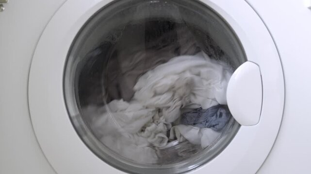Detailed close-up of laundry spinning inside stainless steel washing machine. Concept washing technology and household chores.
