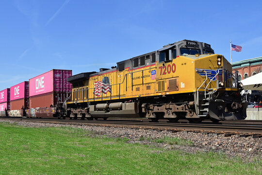 A single Union Pacific Railroad locomotive leads a container train through a suburban Chicago community.