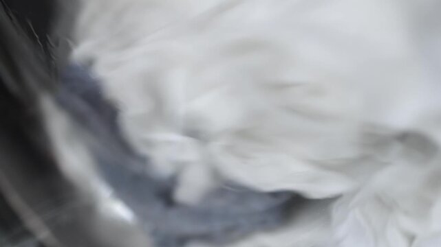 Laundry items swirling inside a washing machine drum, showcasing the continuous motion of fabric as it tumbles and mixes during the wash cycle