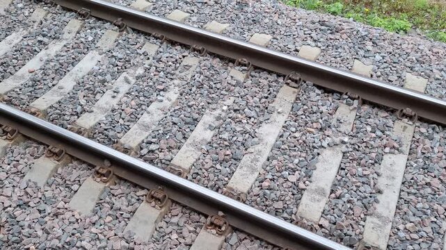 Close-up high angle view of railway tracks with steel rails and concrete sleepers on gray gravel ballast. Transportation infrastructure and durable track construction