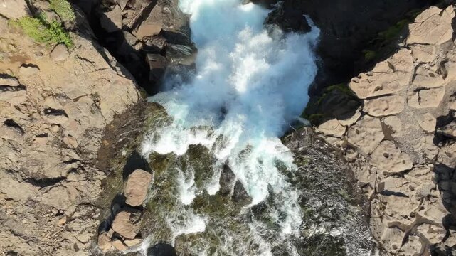 Aerial flight over the wild Nykurhylsfoss (Sveinsstekksfoss) waterfall on a summer day in east Iceland. Top down view.