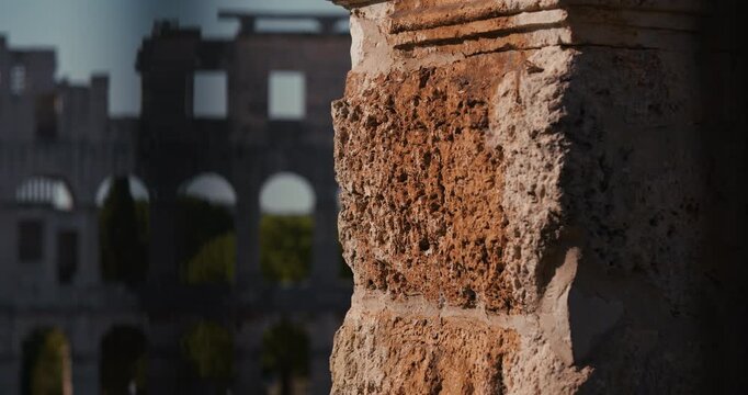 Close view of a weathered stone column detail inside the ancient Pula Arena Roman amphitheater with blurred arches in the background in Pula Croatia.