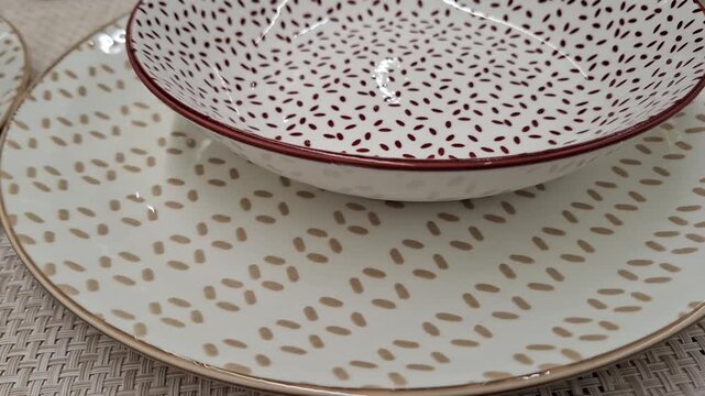 Close-up view of a modern ceramic dinnerware set featuring a deep bowl and flat plate. Elegant dotted patterns in beige and burgundy colors add a contemporary texture to stylish kitchenware