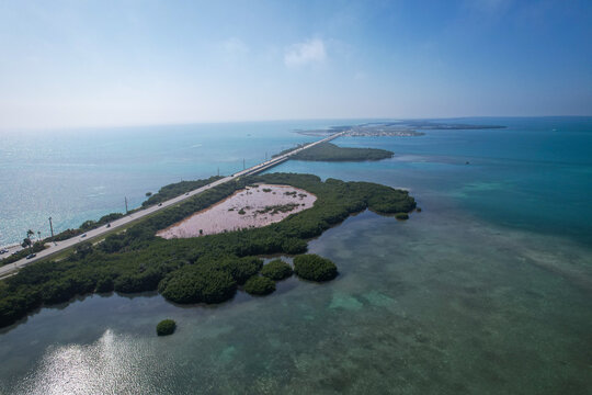 Aerial view of The Overseas Highway stretching across lush green mangrove islands and turquoise ocean waters under a clear blue sky Key Largo, Florida, United States.