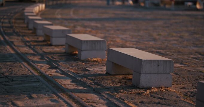 Concrete benches aligned on stone pavement in low sunlight near the exterior of the Pula Arena in Pula Croatia.