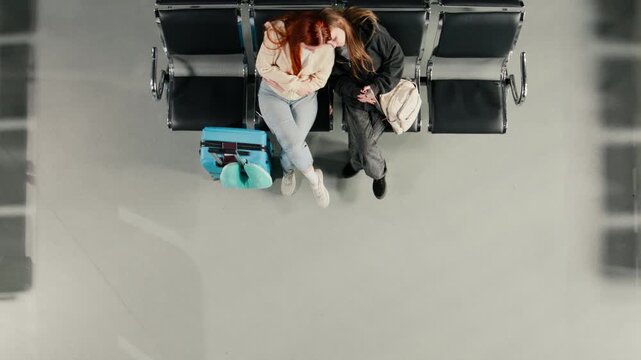 Top down view of people waiting in airport, checking flight schedule screen. Passengers carrying baggage in airplane departure terminal looking at flight timetable display, high angle shot
