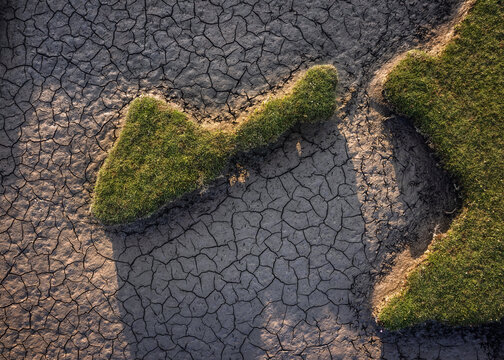 Aerial view of the parched cracked earth and patches of green grass at Portmarnock Beach under warm sunlight County Dublin, Ireland.
