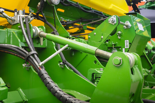 Technical detail of an agricultural hydraulic system with adjustable cylinder, high-pressure hoses, and integrated chain drive.