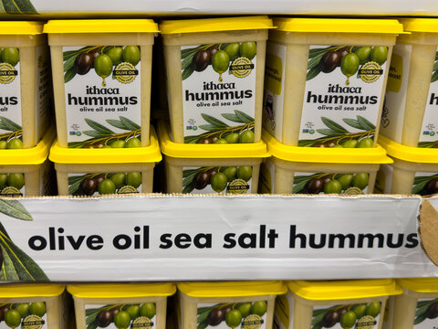 Prosper, Texas, USA - May 06th, 2026: Ithaca Hummus Olive Oil Sea Salt yellow lid square plastic tubs stacked in Costco Wholesale warehouse store