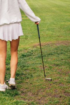 defocused girl in white golf skirt on mini golf course