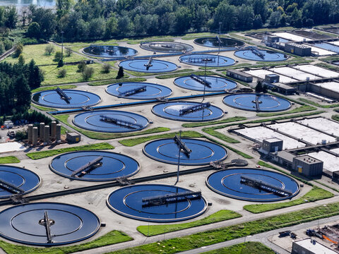 Aerial view of the Impianto depurazione water treatment plant with circular sedimentation tanks surrounded by green lawns and trees Castiglione Torinese, Piedmont, Italy.