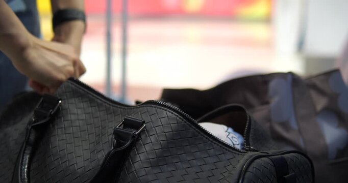 Cinematic close-up of hands zipping up a black travel bag, holiday journey and packing completion concept