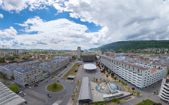 Aerial view of Esplanade Kongresshaus 11 featuring modern architecture, a large white canopy, and a roundabout under a cloudy sky in Biel Bienne, Canton of Bern, Switzerland.
