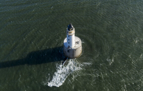 Aerial view of Rattray Head Lighthouse standing in the choppy North Sea with its long shadow cast on the dark green water Peterhead, Scotland, United Kingdom.