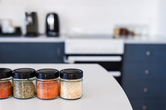 tidy spices and herbs in matching jars on kitchen countertop with soft kitchen bokeh background