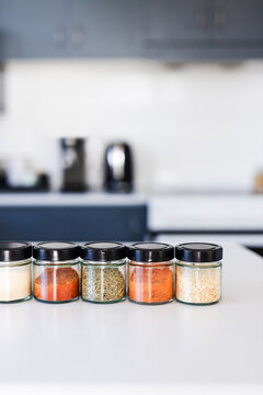tidy spices and herbs in matching jars on kitchen countertop with soft kitchen bokeh background