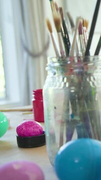 Vertical video: Panning cam revealing pastel eggs and brushes at home craft table showing progress