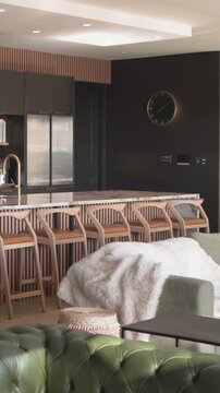 Vertical video: Panning camera moving right forward revealing marble island, stools, kitchen clock
