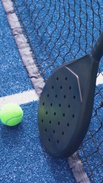 Vertical video: Entering black paddle nudging ball onto white line near net on court, copy space