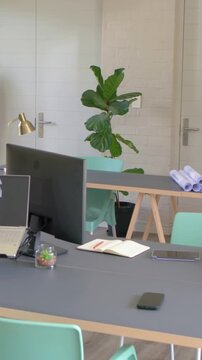 Vertical video: Panning camera revealing desk, laptop floorplan at home office to show workspace