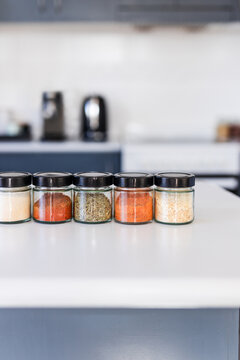 tidy spices and herbs in matching jars on kitchen countertop with soft kitchen bokeh background
