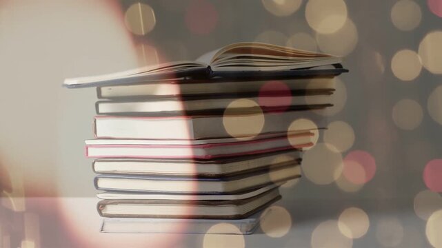 Soft glow entering left moving across notebook stack, bokeh shifting, highlighting open notebook
