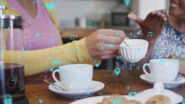 Daughter spooning sugar into cup offering mom care in kitchen, tech icons drifting over hands, cups