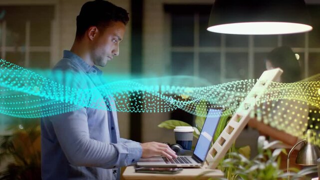 Man typing at standup desk for work in tech office, dotted waveform sweeping across revealing peer